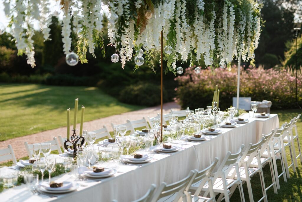 Lange Hochzeitstafel im Garten unter Blauregen für eine kleine Hochzeit mit rund 30 Gästen