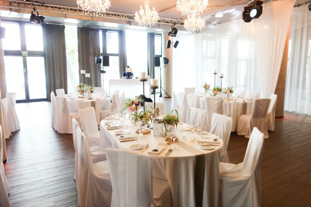 Festlich eingedeckter Hochzeitssaal mit Kronleuchtern und Glasfront im Westhafen Pier 1 in Frankfurt