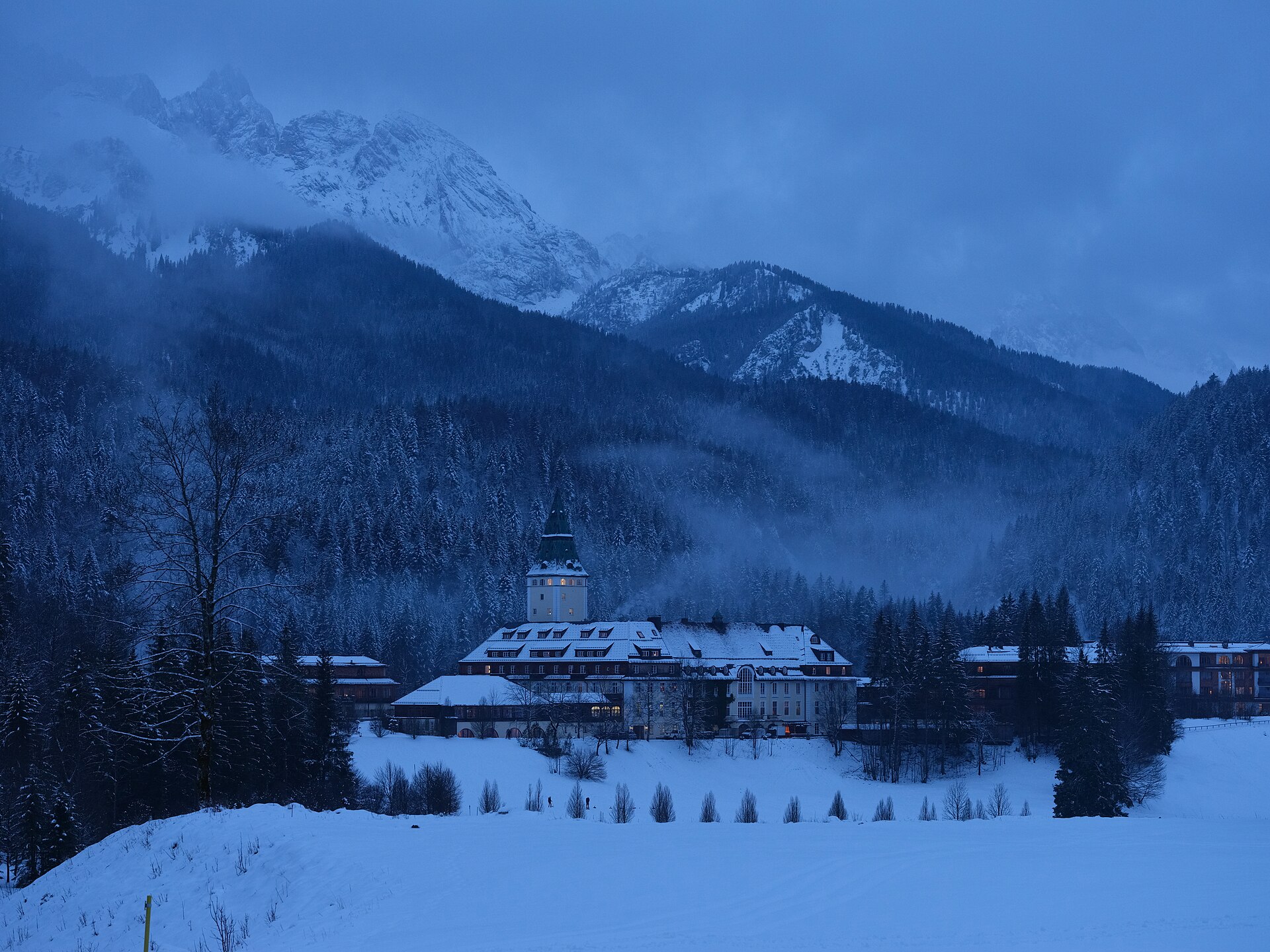 Schloss Elmau im Winter mit verschneiten Bergen – Location für eine Winterhochzeit in den bayerischen Alpen
